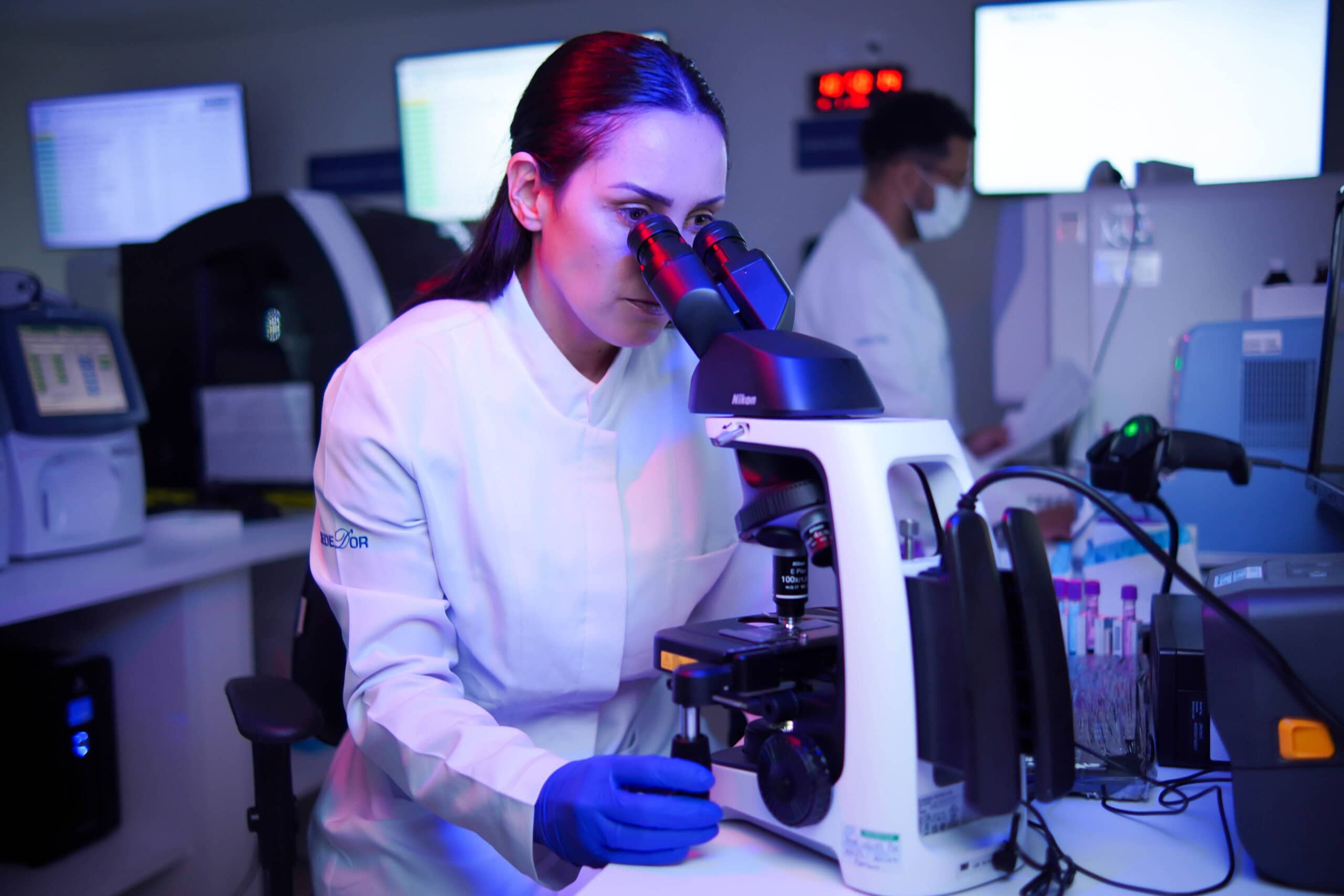 Mulher branca - Homem negro - Te╠ücnicos de laborato╠ürio - Jaleco branco - EPI - Ana╠ülise de material - Microsco╠üpio - Horizontal