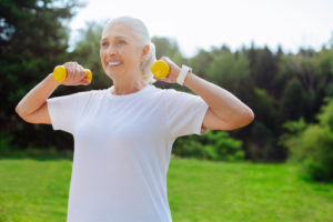 mulher idosa fazendo musculação ao ar livre