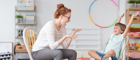 Psicóloga conversa com uma criança que está com as mãos para cima brincando. Um dos sintomas do TDAH é a falta de atenção e concentração