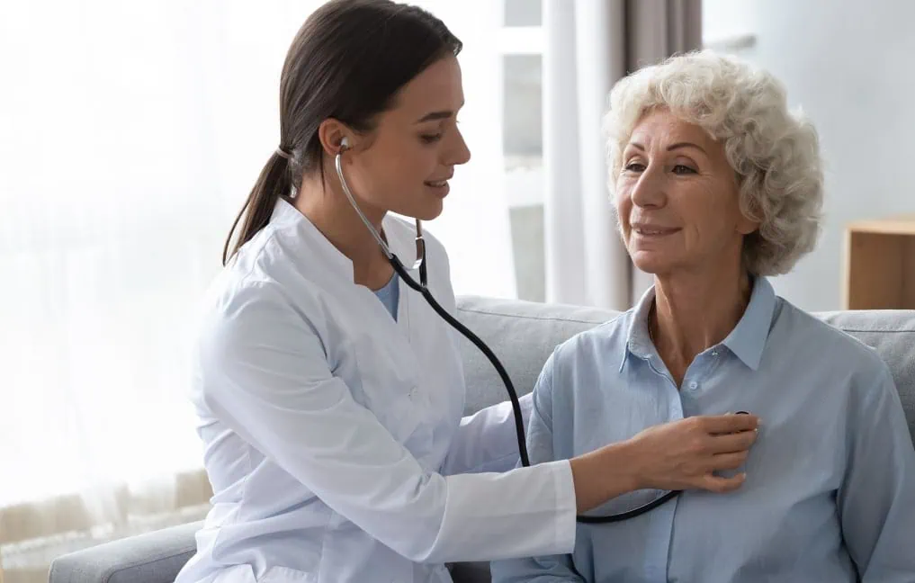 Médica atendendo médica idosa.