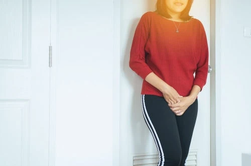 mulher com as mãos na virilha segurando xixi