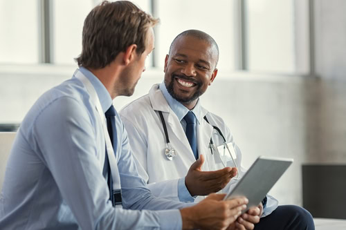 Two,Mature,Smiling,Doctors,Having,Discussion,About,Patient,Diagnosis,,Holding