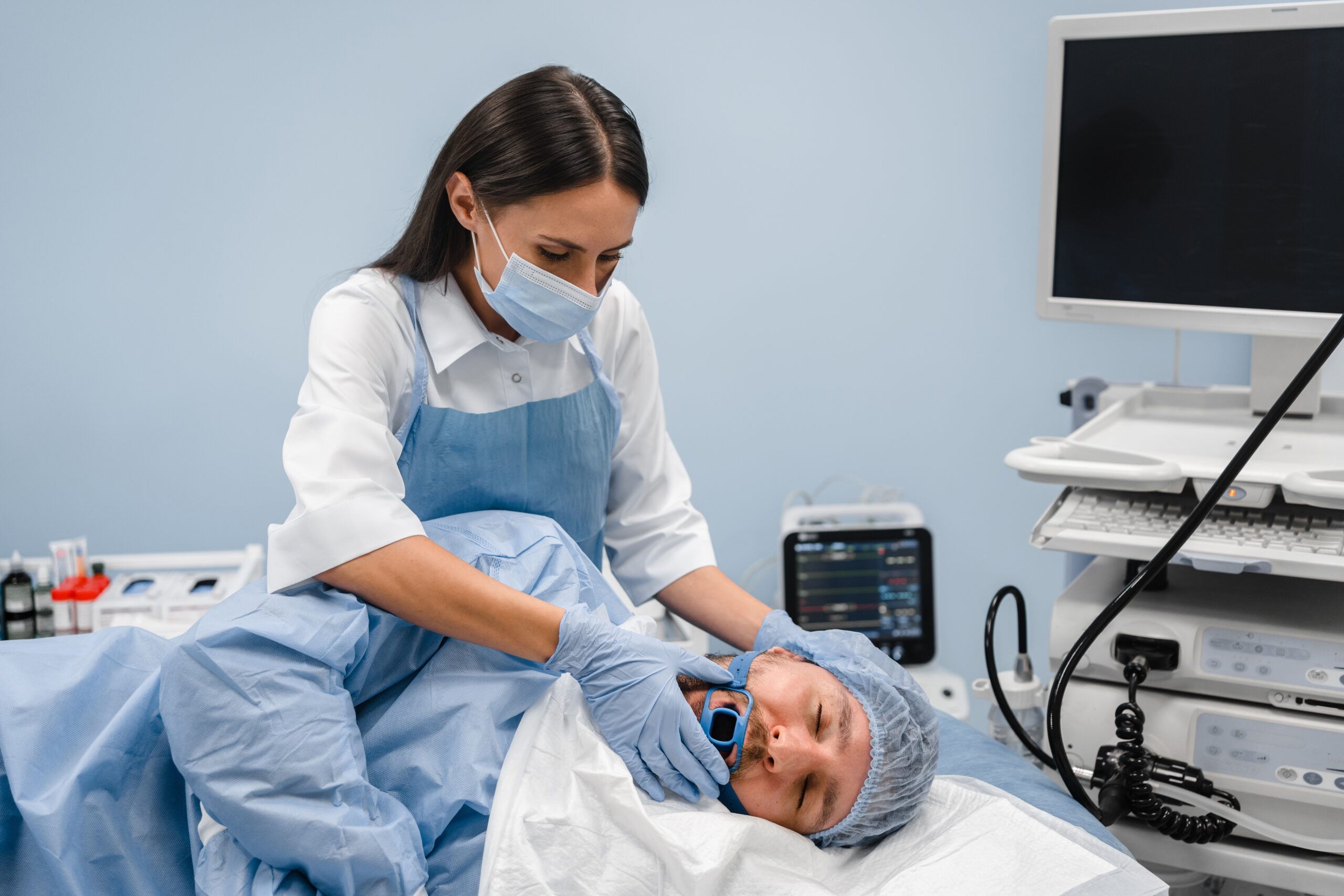 Profissional da saúde prepara paciente sedado para a realização de endoscopia digestiva em ambiente hospitalar.