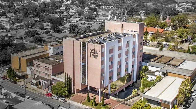 Vista aérea da fachada do hospital Novo Atibaia, no estado de SP, rodeado por outros prédios menores, casas e avenida