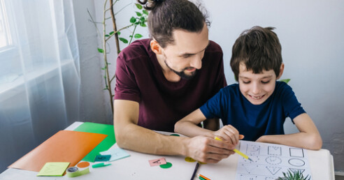 criança autista e pai ensinando e ajudando no dever de casa