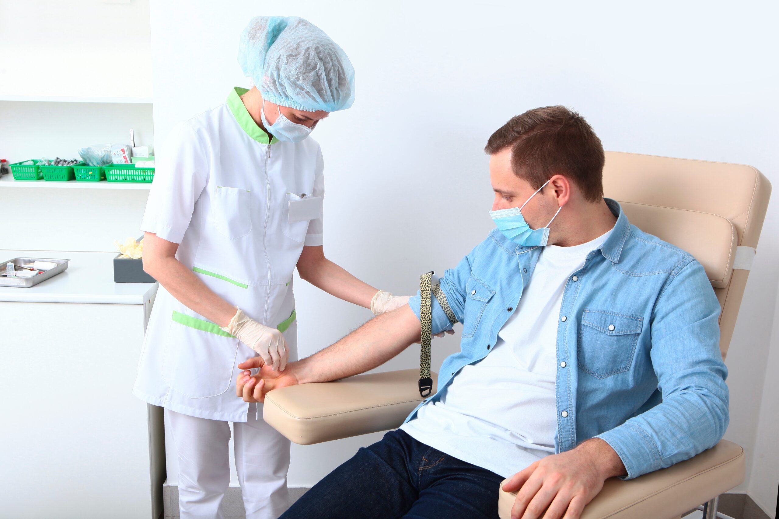 Profissional de saúde coletando sangue de um homem em um consultório.