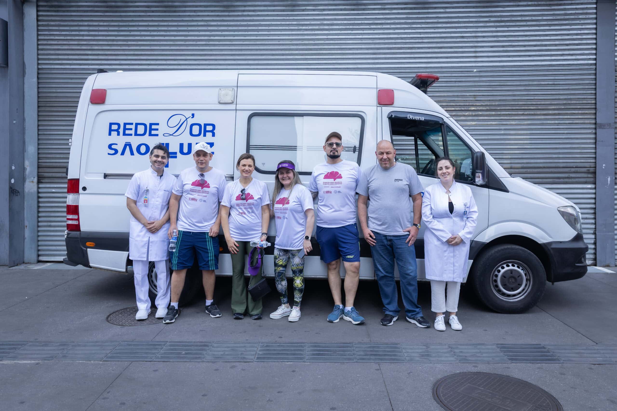 Ambulância com logo Rede D'Or São Luiz e profissionais na frente