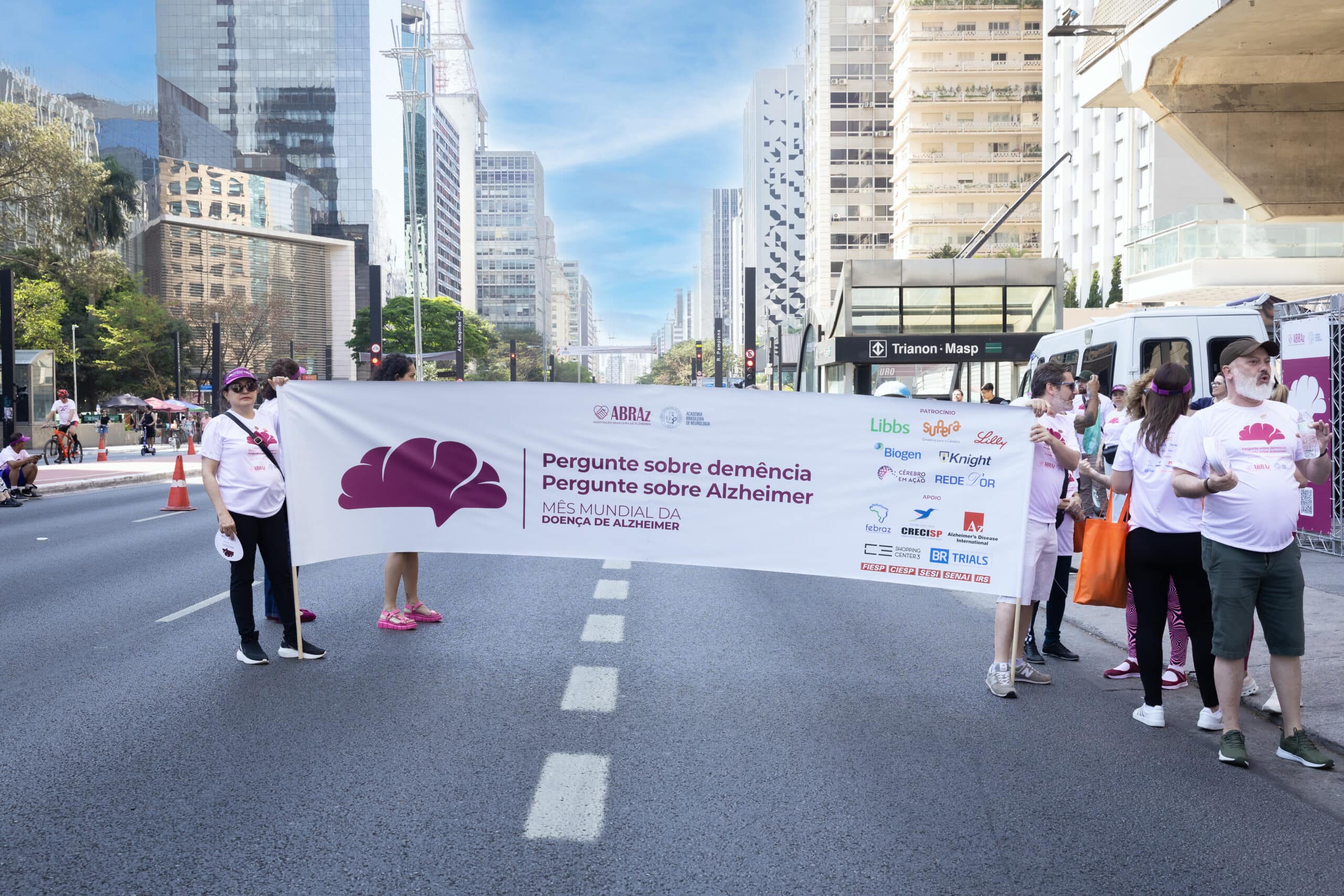 Pessoas na caminhada segurando banner do evento