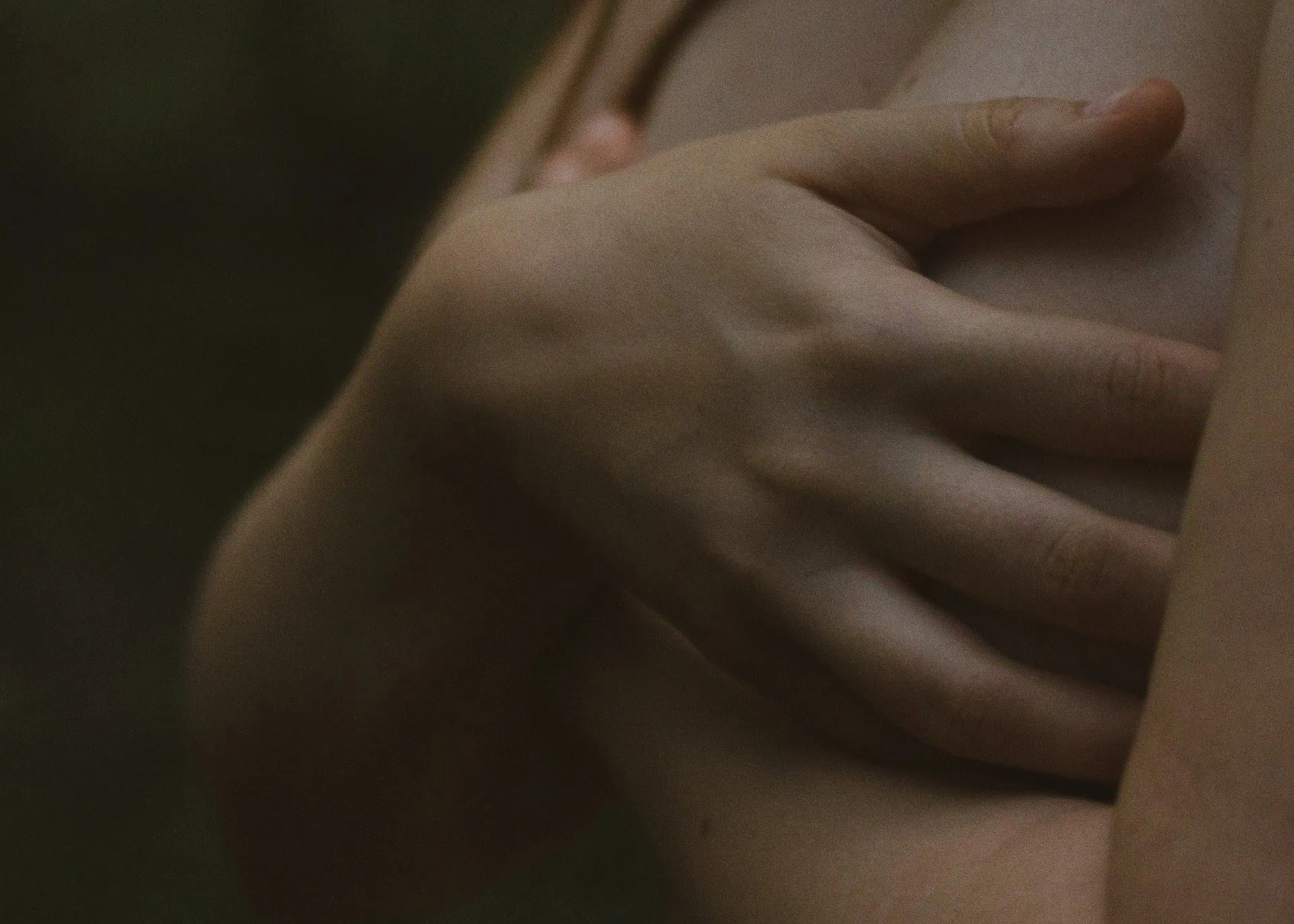 Fotografia em close mostra mulher de lodo, cobrindo os seios com as mãos.
