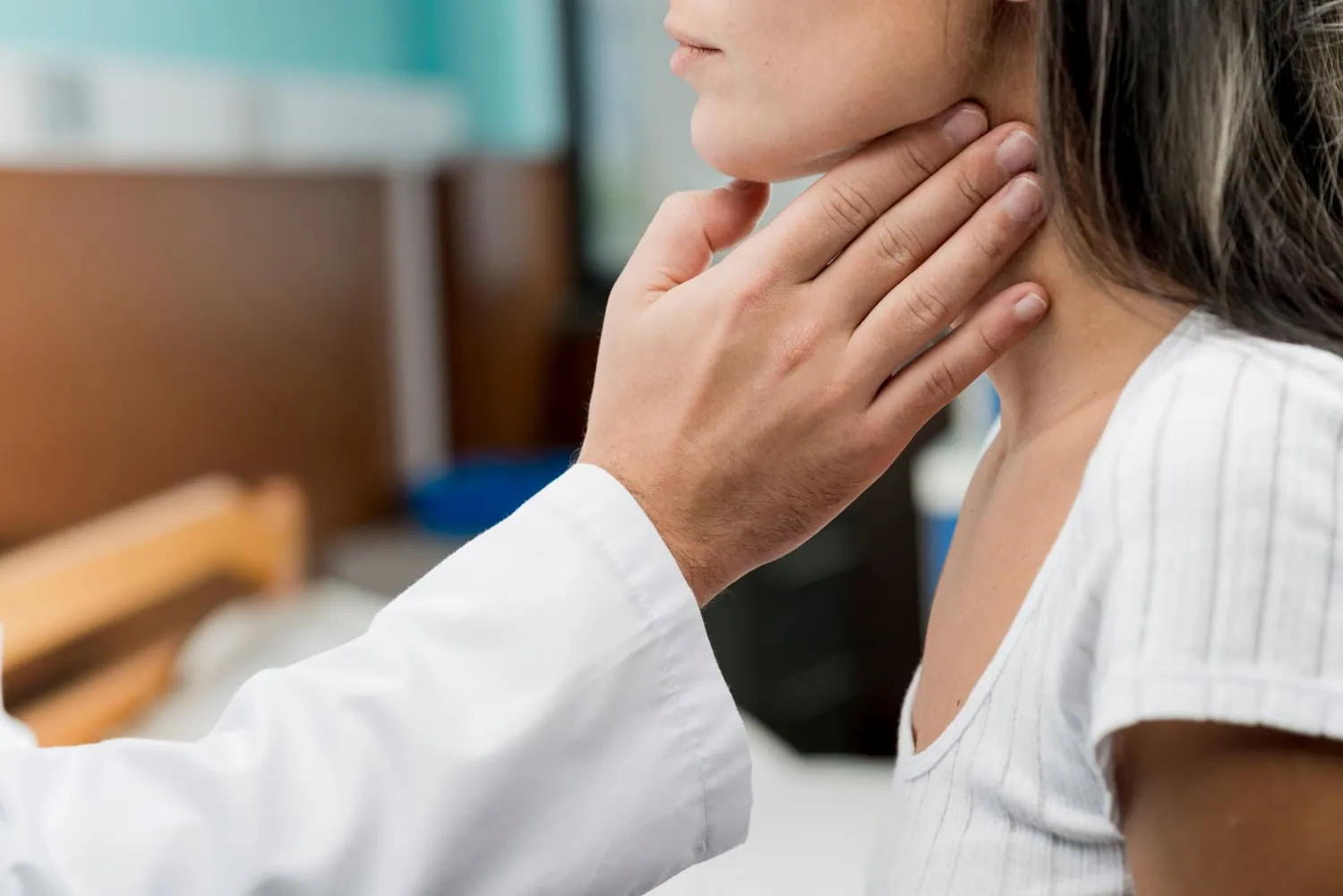 Imagem mostra médico examinando a tireoide de uma mulher.