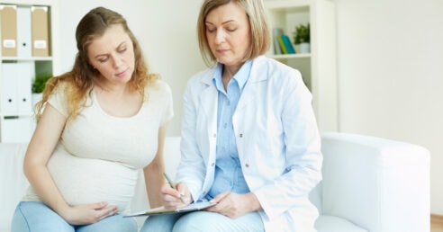 ALT: mulher grávida em consulta médica.