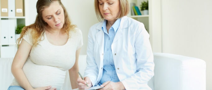 ALT: mulher grávida em consulta médica.