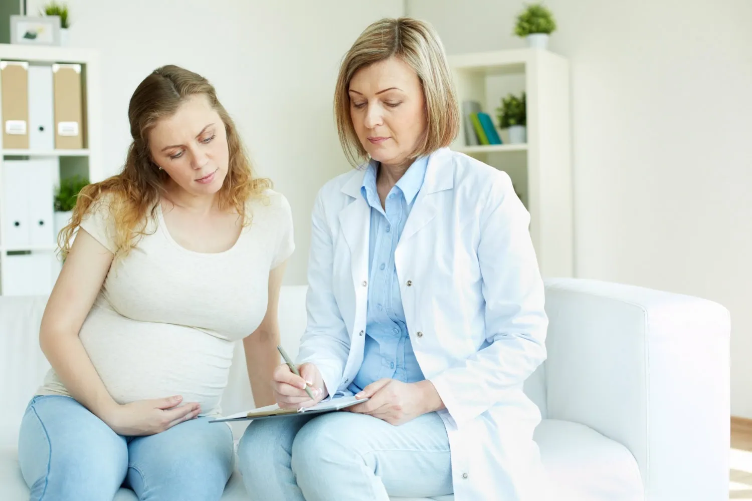 ALT: mulher grávida em consulta médica.