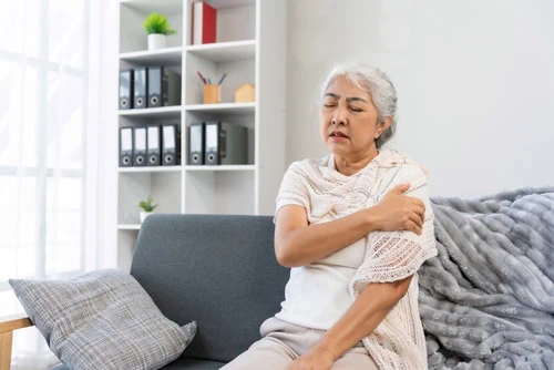 Senior,Woman,Suffering,From,Shoulder,Pain,,Holding,Arm,While,Sitting
