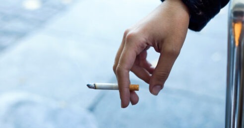 ALT: mão de uma mulher segurando um cigarro.